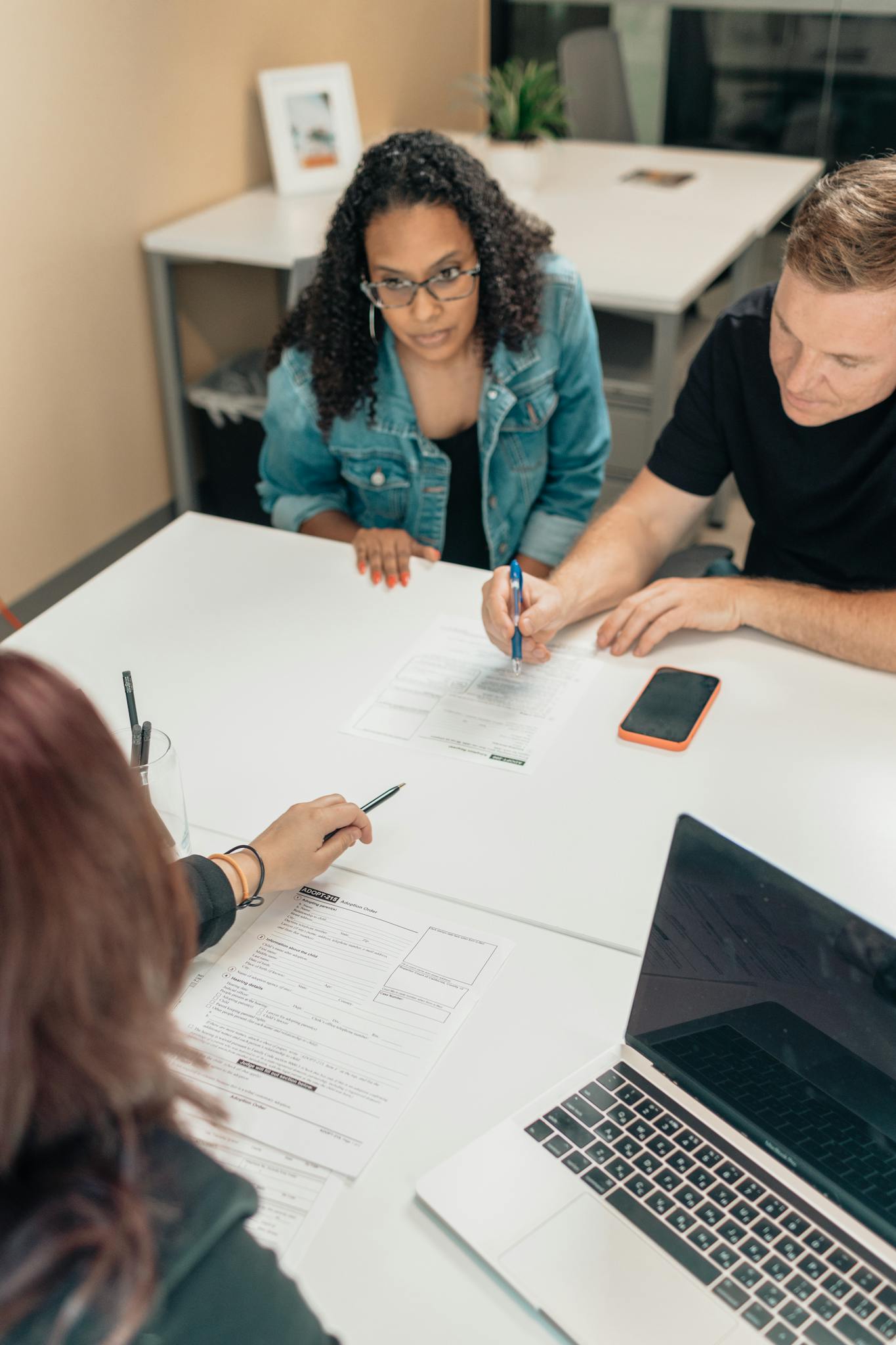 A couple discusses adoption papers with a professional in an office environment.